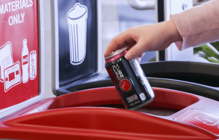 A woman recycling a can of Coca-Cola