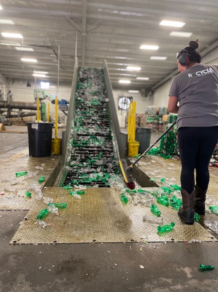 Worker sweeps up recycled Sprite bottles